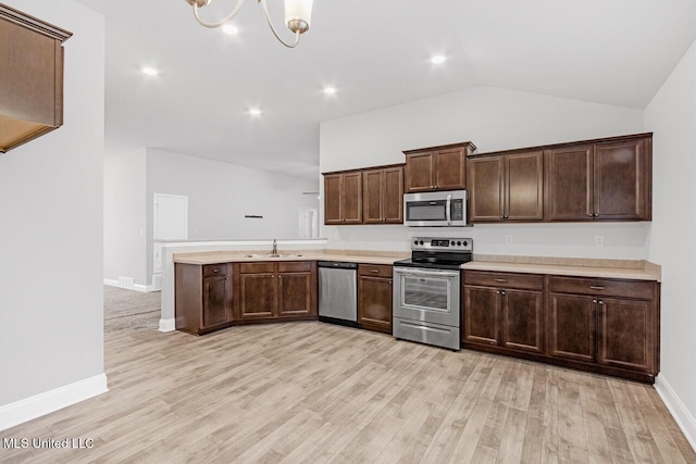 kitchen featuring vaulted ceiling, a chandelier, light wood-type flooring, and appliances with stainless steel finishes