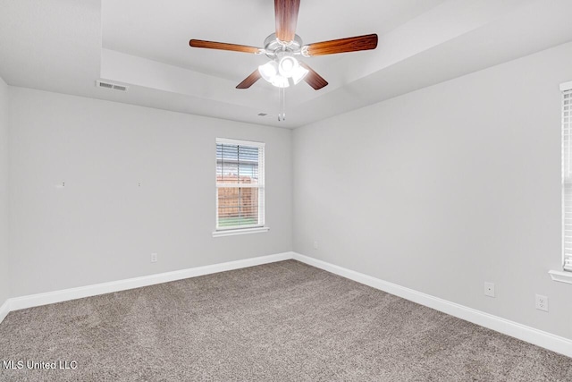 carpeted spare room with ceiling fan and a tray ceiling