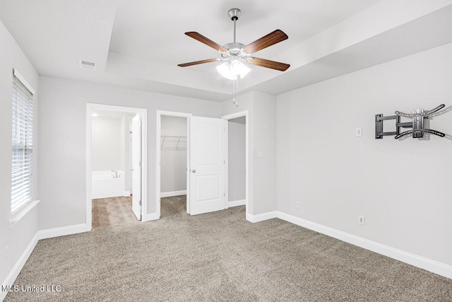 unfurnished bedroom with carpet flooring, multiple windows, a spacious closet, and ceiling fan