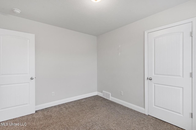 unfurnished room with a textured ceiling and carpet floors