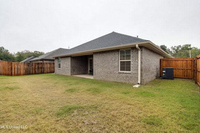 rear view of house featuring central AC unit and a lawn