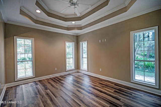 empty room with crown molding, ceiling fan, dark wood-type flooring, and a raised ceiling