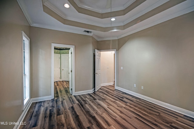 unfurnished bedroom with dark wood-type flooring, a raised ceiling, and ornamental molding