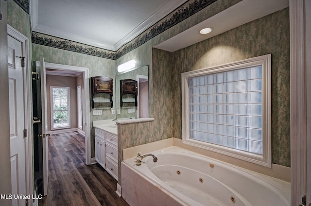 bathroom with a textured ceiling, wood-type flooring, ornamental molding, a bath, and vanity