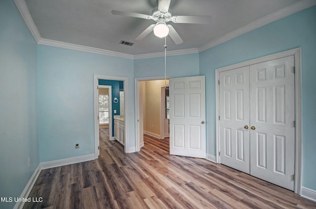 unfurnished bedroom featuring dark wood-type flooring, crown molding, a closet, and ceiling fan