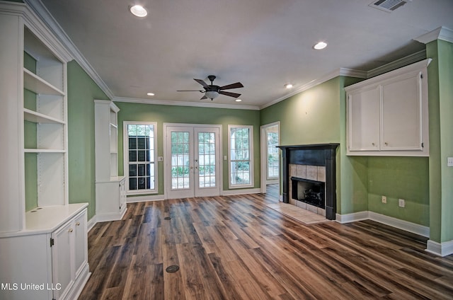 unfurnished living room featuring crown molding, dark hardwood / wood-style floors, a tile fireplace, and ceiling fan