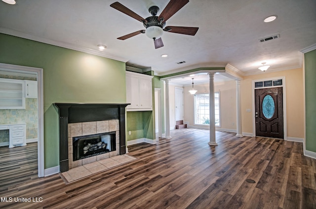 unfurnished living room with decorative columns, crown molding, dark hardwood / wood-style flooring, a fireplace, and ceiling fan