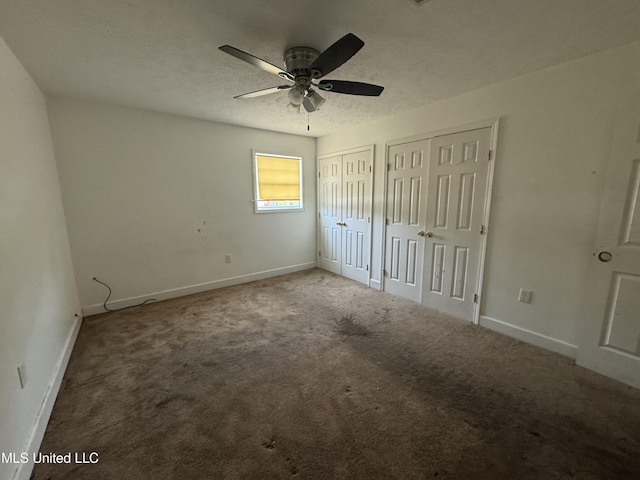 unfurnished bedroom with ceiling fan, two closets, and carpet floors