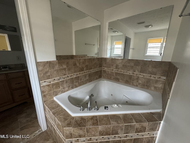 bathroom featuring tiled tub and vanity