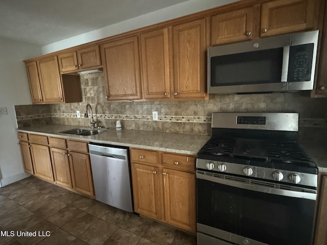 kitchen featuring sink, dark tile patterned flooring, stainless steel appliances, and tasteful backsplash