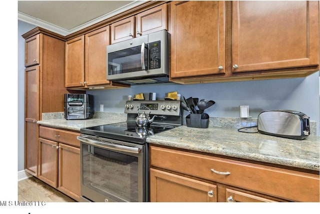 506 Loposser Ave, Gulfport, MS 39507 - kitchen featuring stainless steel appliances, crown molding, brown cabinetry, light stone countertops, and light wood-type flooring