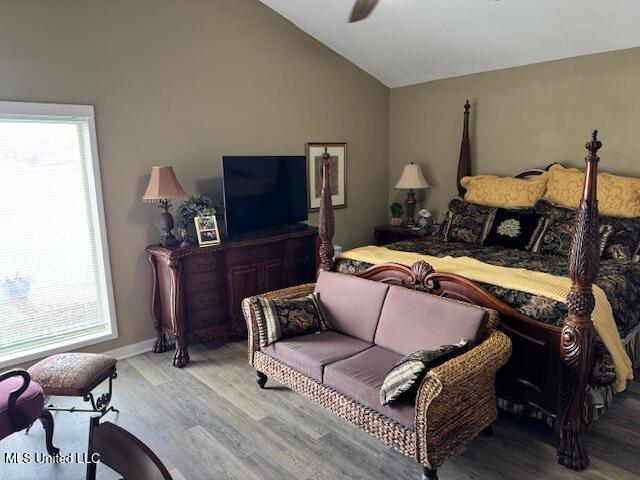 bedroom with lofted ceiling, multiple windows, and wood finished floors