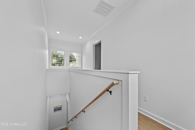 stairway with wood finished floors, recessed lighting, baseboards, and crown molding