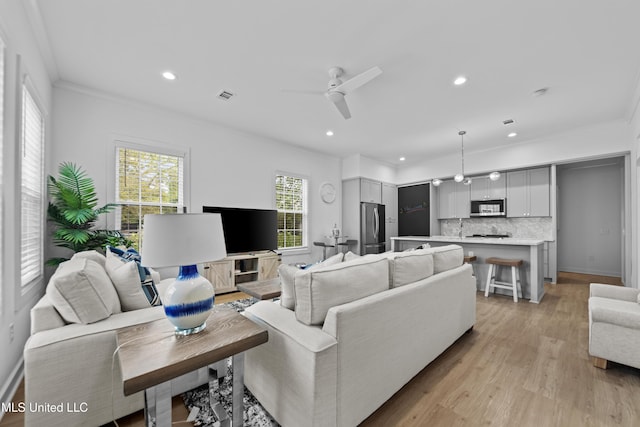 living room with ornamental molding, a ceiling fan, recessed lighting, and light wood finished floors