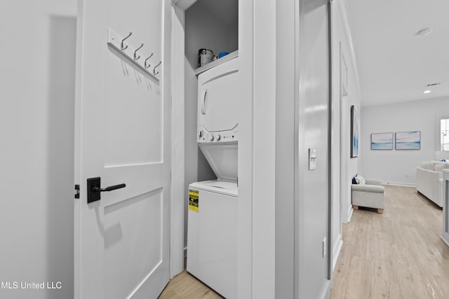 clothes washing area featuring stacked washer and clothes dryer, light wood-style flooring, and recessed lighting
