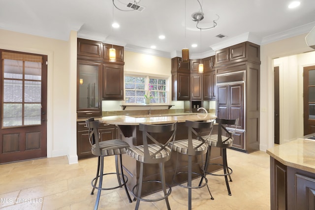 kitchen with a kitchen breakfast bar, dark brown cabinetry, crown molding, and pendant lighting