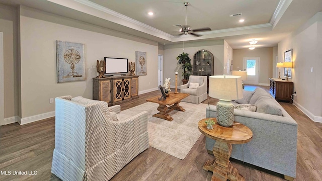 living room with ornamental molding, a raised ceiling, and hardwood / wood-style floors