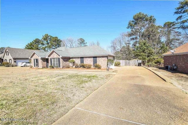 ranch-style house with central AC unit, concrete driveway, a front yard, and fence