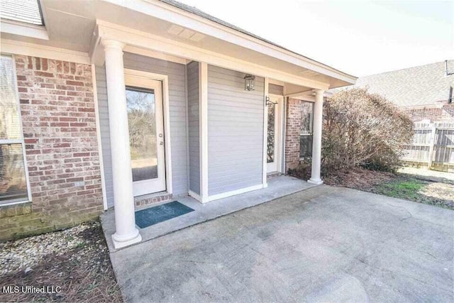 property entrance with fence and brick siding