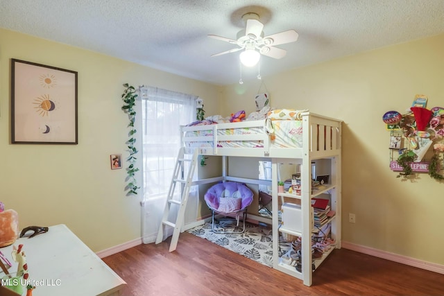 bedroom featuring baseboards, a textured ceiling, wood finished floors, and a ceiling fan