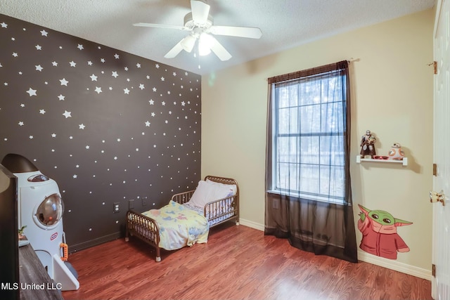 bedroom with ceiling fan, baseboards, a textured ceiling, and wood finished floors