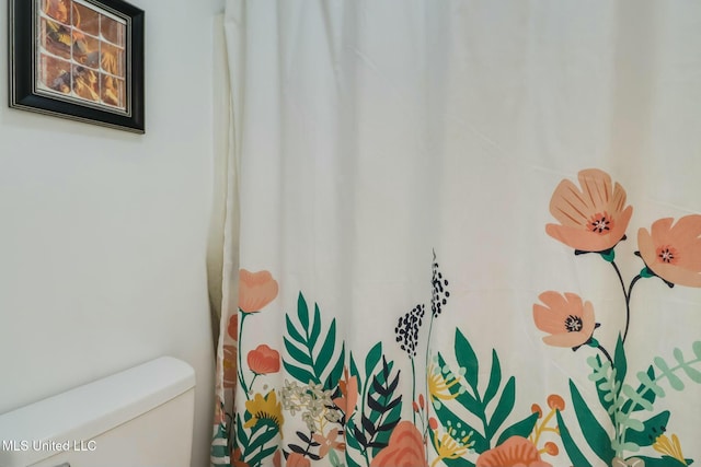 details with a shower with curtain and toilet