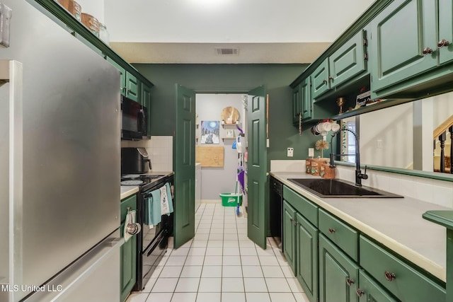 kitchen with a sink, green cabinetry, black appliances, and light countertops