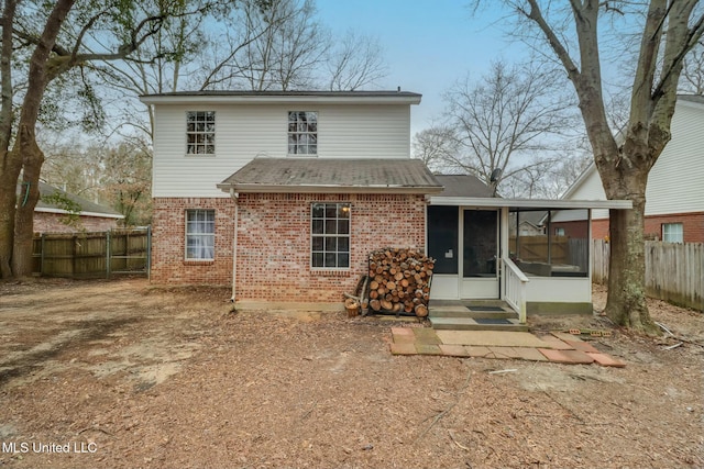 rear view of property featuring a fenced backyard, brick siding, and a sunroom