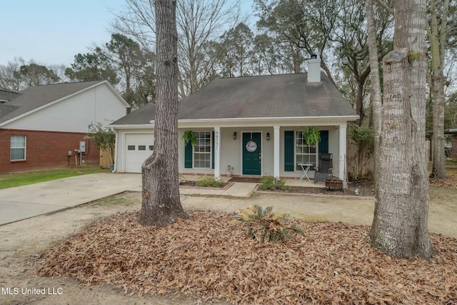 view of front of house with covered porch, a chimney, concrete driveway, a fire pit, and a garage