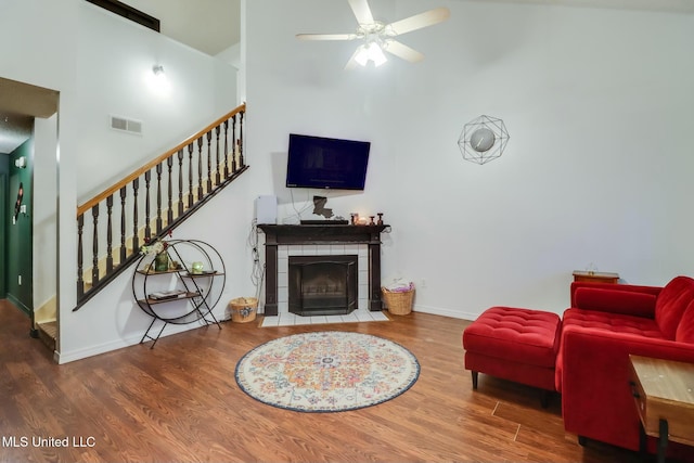 living area featuring visible vents, stairs, a fireplace, wood finished floors, and a ceiling fan