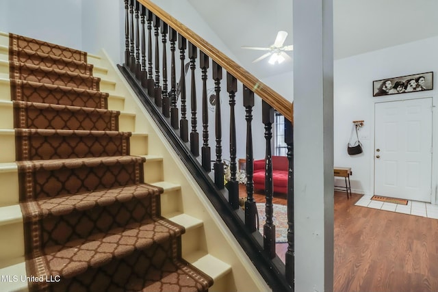 stairway with a ceiling fan and wood finished floors