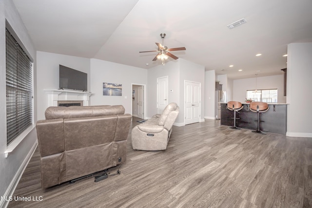 living room featuring visible vents, a ceiling fan, wood finished floors, a fireplace, and baseboards