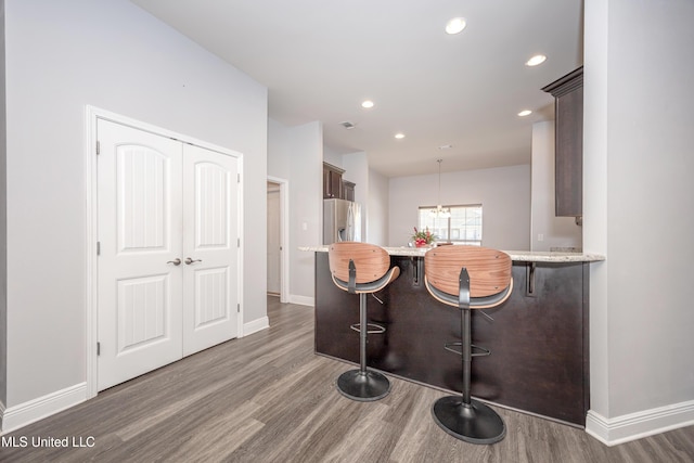 kitchen featuring a kitchen breakfast bar, wood finished floors, baseboards, and stainless steel fridge with ice dispenser