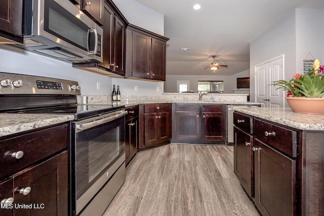 kitchen with dark brown cabinets, light stone countertops, light wood-type flooring, appliances with stainless steel finishes, and a ceiling fan