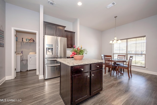 kitchen featuring visible vents, stainless steel refrigerator with ice dispenser, washer and clothes dryer, dark brown cabinets, and dark wood-style flooring