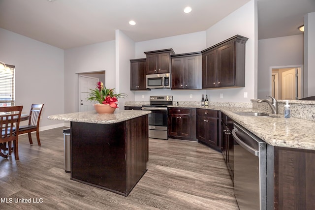 kitchen featuring dark brown cabinets, appliances with stainless steel finishes, wood finished floors, and a sink