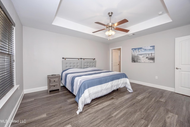 bedroom with a tray ceiling, visible vents, and wood finished floors