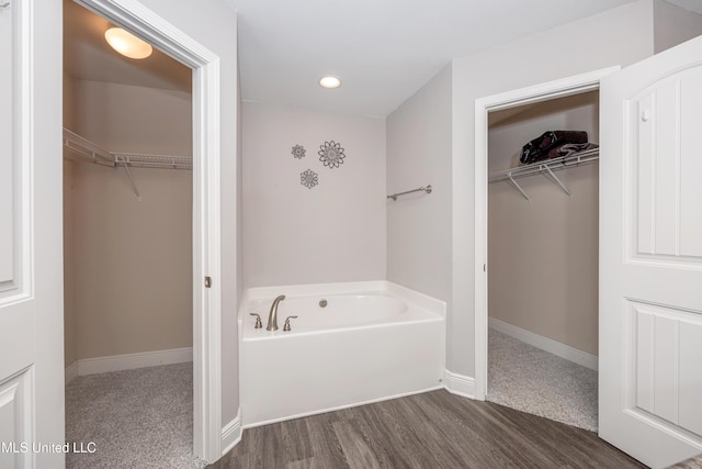 full bath featuring a spacious closet, baseboards, recessed lighting, wood finished floors, and a bath