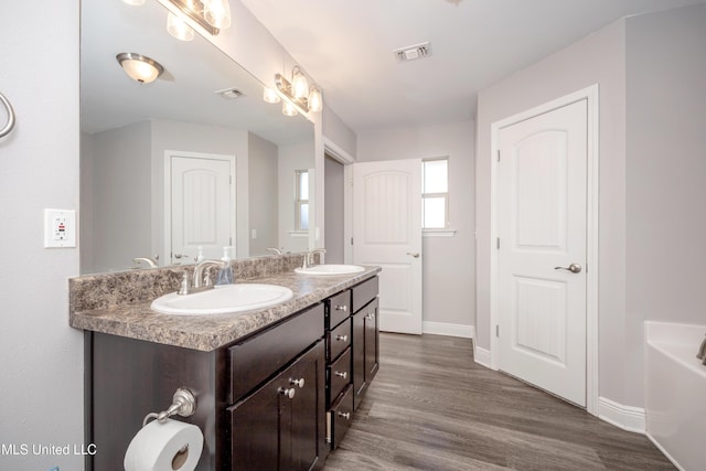 bathroom with visible vents, wood finished floors, and a sink