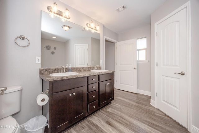 full bathroom with visible vents, toilet, wood finished floors, and a sink