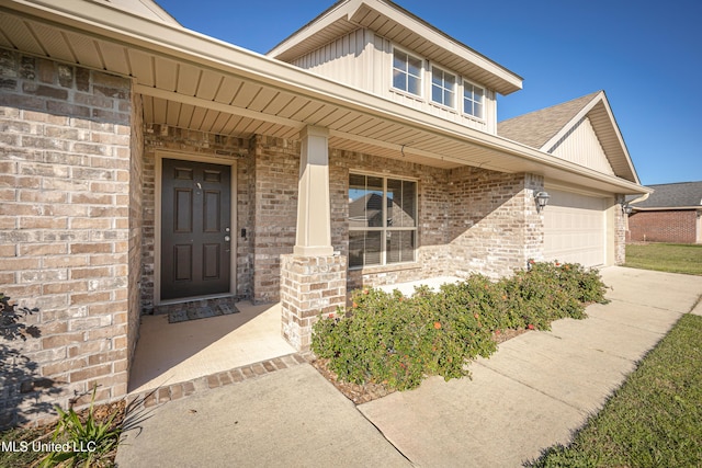 property entrance with brick siding, board and batten siding, covered porch, a garage, and driveway