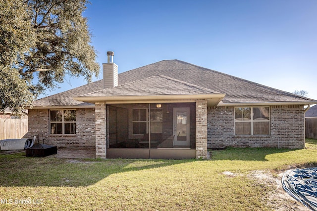 rear view of house with brick siding, a yard, and fence