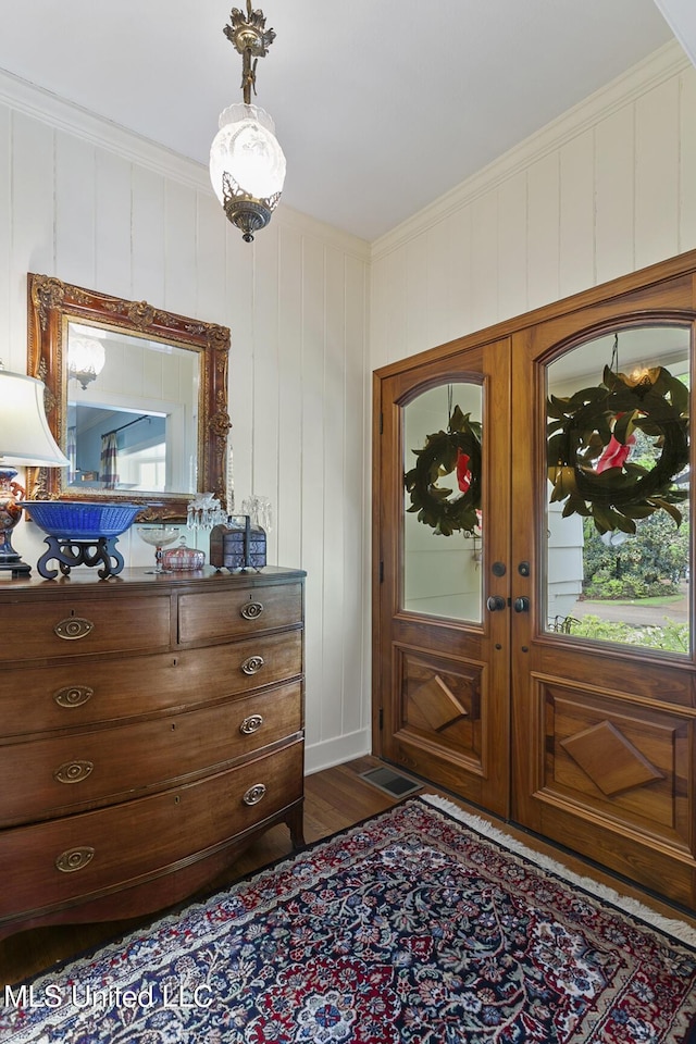 foyer entrance with dark hardwood / wood-style flooring, crown molding, and french doors