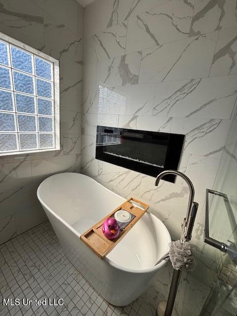 bathroom with a high end fireplace, tile walls, and a tub