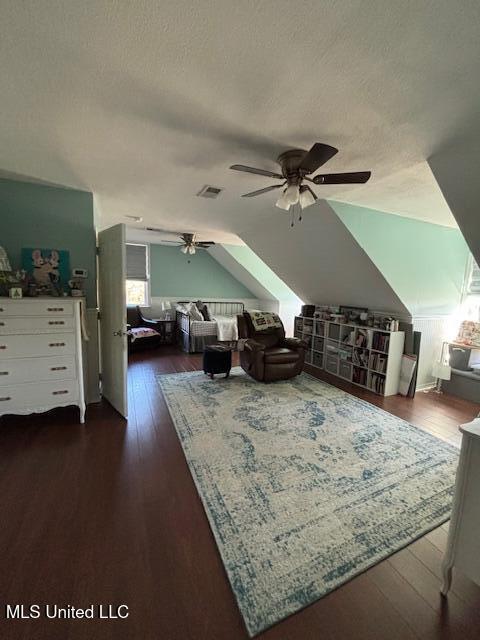 living room featuring dark hardwood / wood-style flooring, ceiling fan, lofted ceiling, and a textured ceiling