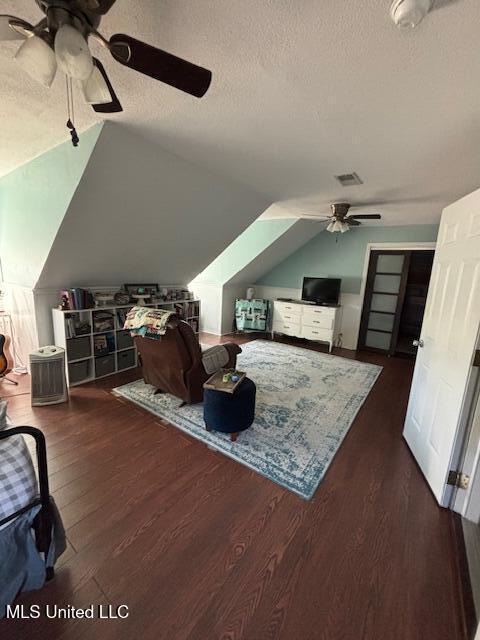 bedroom featuring dark wood-type flooring, ceiling fan, vaulted ceiling, and a textured ceiling