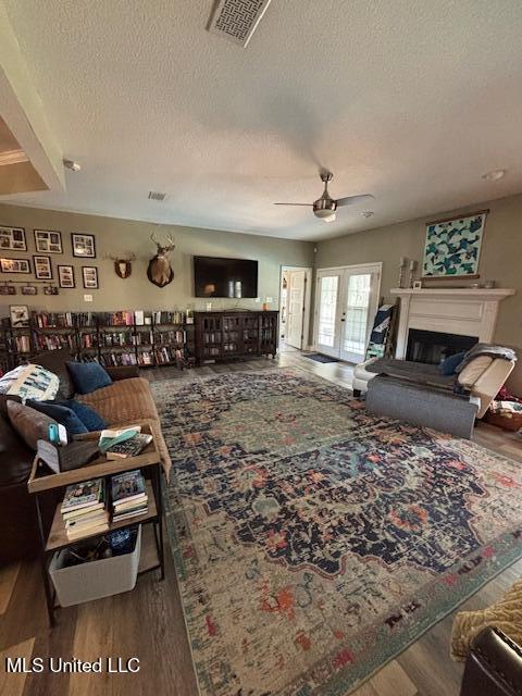 living room featuring ceiling fan, wood-type flooring, and a textured ceiling