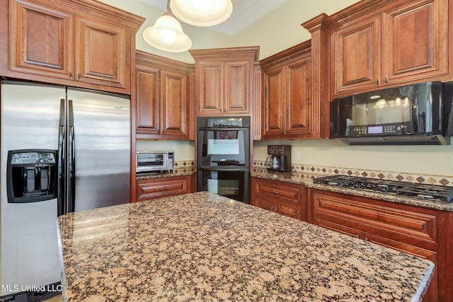 kitchen with dark stone countertops, pendant lighting, black appliances, and a center island