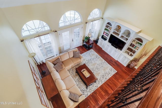 living room featuring french doors, a towering ceiling, and hardwood / wood-style floors