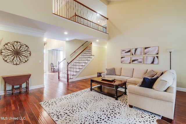 living room featuring hardwood / wood-style flooring, crown molding, and a towering ceiling